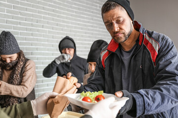 Volunteer giving food to homeless people in warming center
