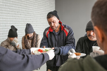 Volunteers giving food to homeless people in warming center