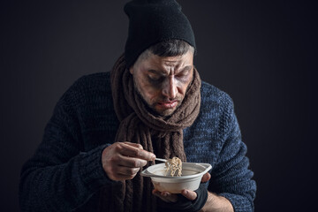 Portrait of poor homeless man with hot soup on dark background