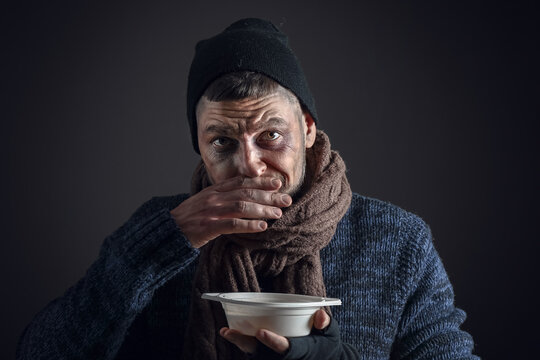 Portrait of poor homeless man with hot soup on dark background