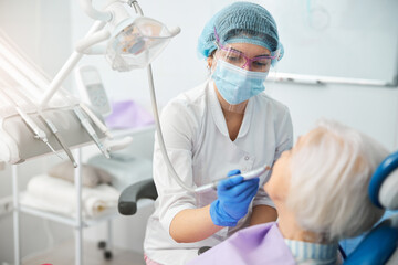 Doctor performing tooth polishing on senior person