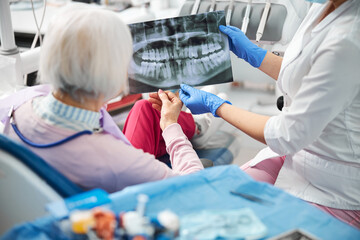 Medical specialist showing her client x-ray with teeth image