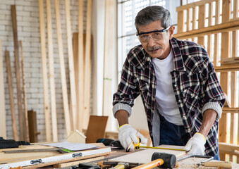 Senior Asian joiner measuring plank