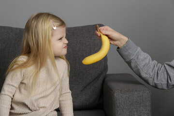 Little girl does not want to eat bananas. Child refusing to eat fruits.