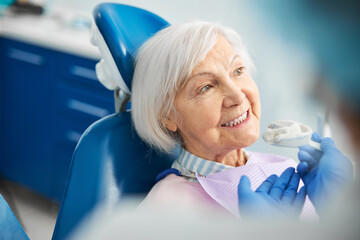 Glad senior female receiving a suggestion of silicone dental impression
