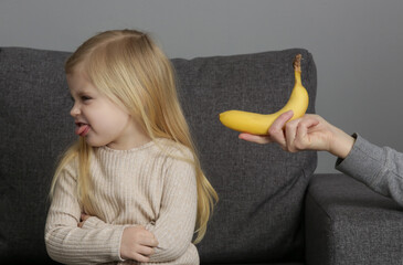 Little girl does not want to eat bananas. Child refusing to eat fruits.