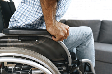 Fototapeta premium Black disabled man sits down on wheelchair at home