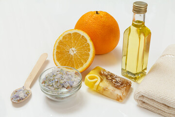 Cut orange with whole one, towel, bottle with aromatherapy oil and sea salt