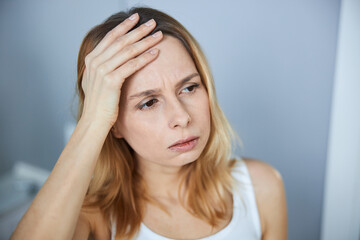 Unhappy young woman having headache at home