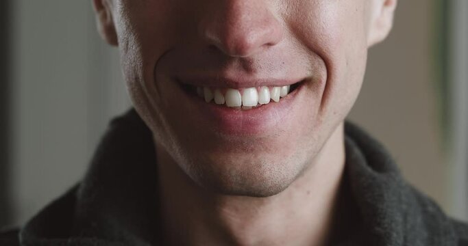 Close up male mouth of smiling with teeth. Young man is smiling indoors, macro shot. Detail of a smile guy.
