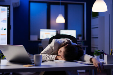 Exhausted overload business woman falling asleep on desk with open laptop while working on marketing project in start up company office. Entrepreneur using modern technology network late at night