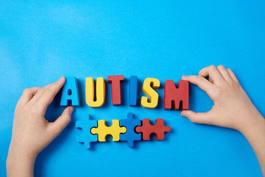 Autistic kid hands holding puzzle jigsaw and word autism, mental health concept. Autism spectrum, disorder. World autism awareness day.