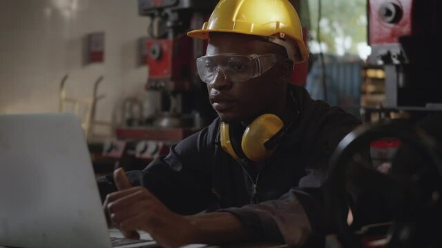 Social distance group of industrial worker, American industrial black young worker man with yellow helmet having teleconference or video conference calls meeting remotely and discussion about project