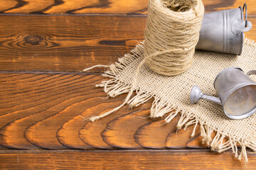 a roll of rope, a minimalistic bucket and a watering can lie on the table