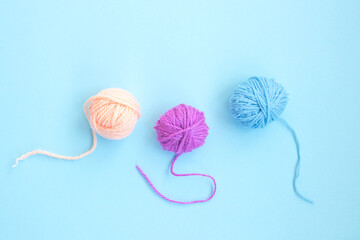 Three skeins of colorful woolen yarn in a row on a light blue background with copy space