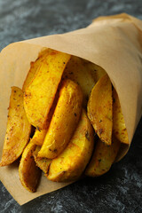 Baking paper with potato wedges on black smokey background