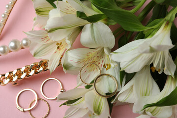 Jewelry and flowers on pink background, close up