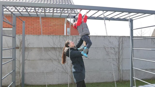 Mother Helping A Child To Climb Monkey Bar