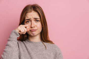 Young ginger upset woman crying and wiping her tears