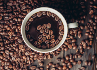 cup with aromatic drink and coffee beans on wooden background top view