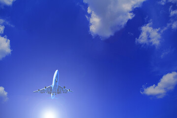 White sun and plane in blue sky with white clouds. Travel by transport