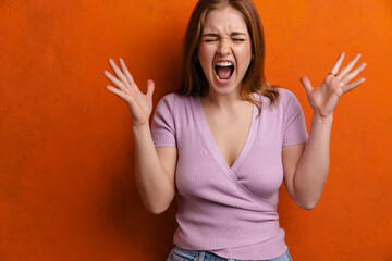 Young ginger angry woman screaming with hand sup at camera