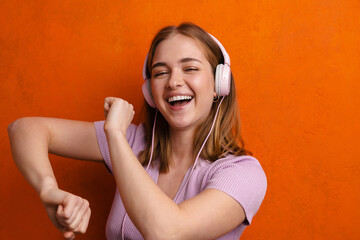 Joyful woman dancing while listening music with headphones