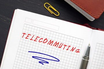 Business concept about TELECOMMUTING with inscription on the page. Telecommuting is an employment arrangement in which the employee works outside of the employer's office.