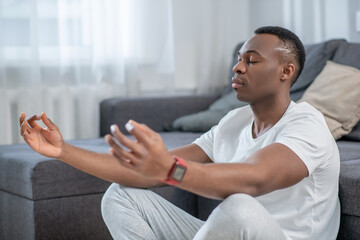 African american guy in white clothes meditating and looking peaceful
