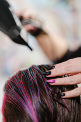 Naklejka premium The hairdresser combs and dries with hairdryer dyed red color hair.