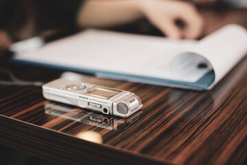 Shallow depth of field (selective focus) image with an audio recorder of a woman journalist during...