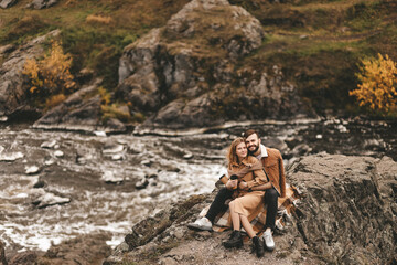 Happy in love romantic young cheerful couple man and woman married travel hiking walk together among the autumn forest and mountains looking for adventure enjoy the local nature, selective focus