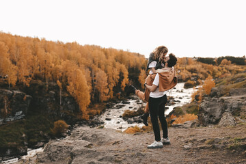 Happy in love romantic young cheerful couple man and woman married travel hiking walk together among the autumn forest and mountains looking for adventure enjoy the local nature, selective focus