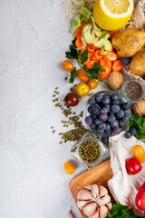 Selection of fresh raw vegetables, fruits and beans on light gray background.