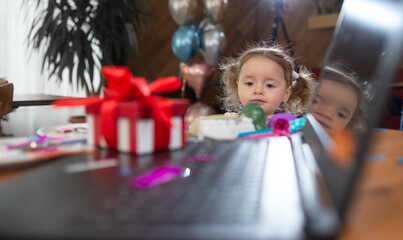 a red box stands near the laptop on the table, a lot of colored confetti. The girl looks at the...