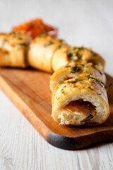 Homemade Chicken Parmesan-Stuffed Garlic Bread on a rustic wooden board on a white wooden background, side view. Close-up.