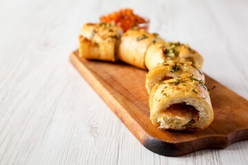 Homemade Chicken Parmesan-Stuffed Garlic Bread on a rustic wooden board on a white wooden background, side view. Copy space.