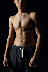 Fototapeta na wymiar male bodybuilder in gray pants naked torso pumped up muscles black background