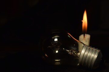 a lamp and one candle blur burning in the dark background, during a power outage. blackout begin.