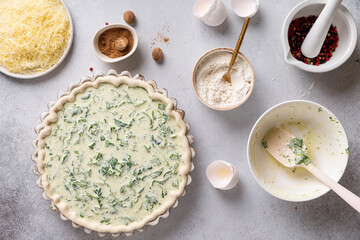 Cooking quiche Lorraine. The rolled out dough is laid out in a ceramic baking form. Liquid filling for tart is poured into the dough. Parmesan cheese, grated for sprinkling the pie.
