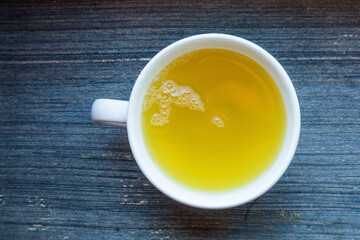 White round porcelain tea cup with fresh herbal green tea. Hot healthy beverage for breakfast. Wooden background. top view geometrical composition. Vitamine cocktail. Raw biological vegan beverage 
