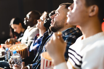 Friends are watching a movie in the cinema. People sit in the armchairs of the cinema and look at the screen