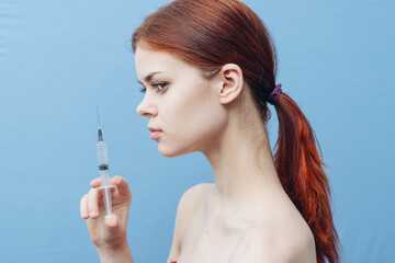 Obraz premium women make injections for rejuvenation on a blue background And syringe in hand side view