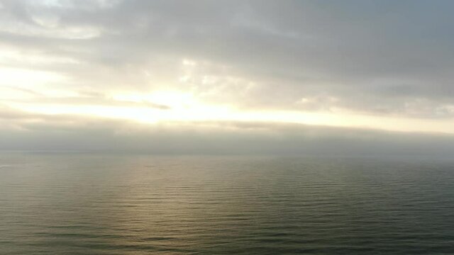 Sunrise over the sea under a cloudy gloomy sky. Aerial view.