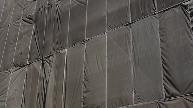 4K Footage Of Brown Tarpaulin Rippling On The Side Of A Building Under Construction, In Singapore.