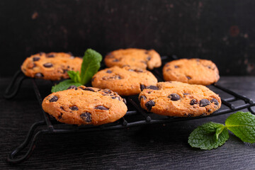 Chocolate chip cookies decorated with mint on a dark background.