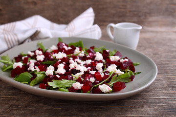 Fresh salad with beetroot, arugula and feta cheese in a plate on a dark background.
