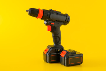 Fototapeta premium Modern black cordless screwdriver, drill with recharge battery on yellow background, copy space for text