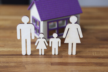 Wooden figurines of parents and children on background of house.