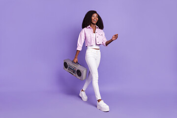 Fototapeta na wymiar Full size photo of young happy cheerful excited african woman go walk hold boombox isolated on violet color background